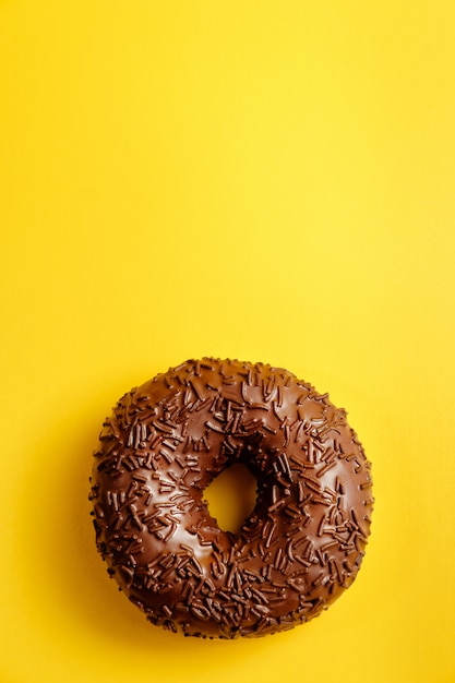 Donut de chocolate na vista superior da parede amarela