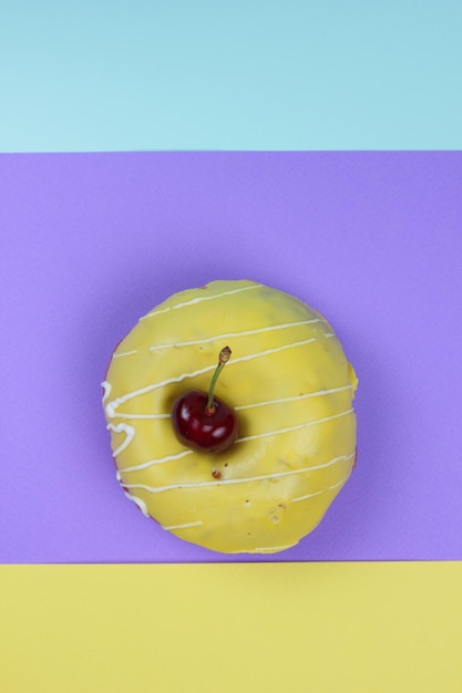 Donut dulce glaseado con cerezas rojas sobre un fondo colorido Vista de primer plano desde arriba