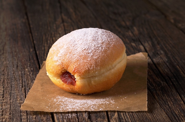 Donut dulce con mermelada en la mesa de madera antigua de cerca