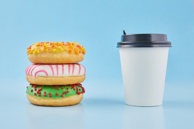 Donut dulce o donut con una taza caliente de té o café recién hecho. Vaso de papel para llevar con donas.