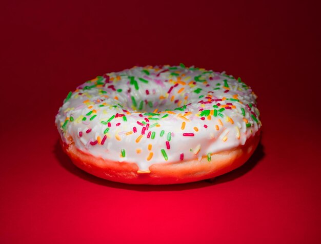 Foto donut esmaltado con salpicaduras de fondo rojo limpio