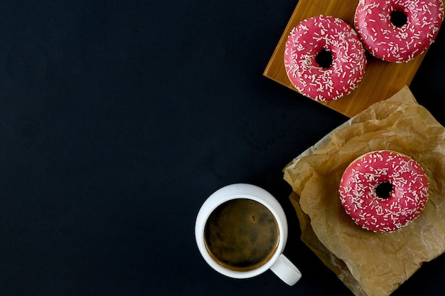 Donut de fresa recién horneado sobre tabla de madera, fondo negro