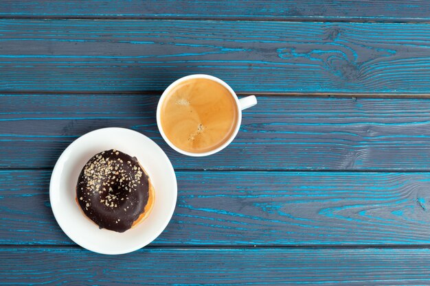 Donut fresco con café en superficie de madera, vista superior