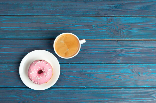 Donut fresco con café en superficie de madera