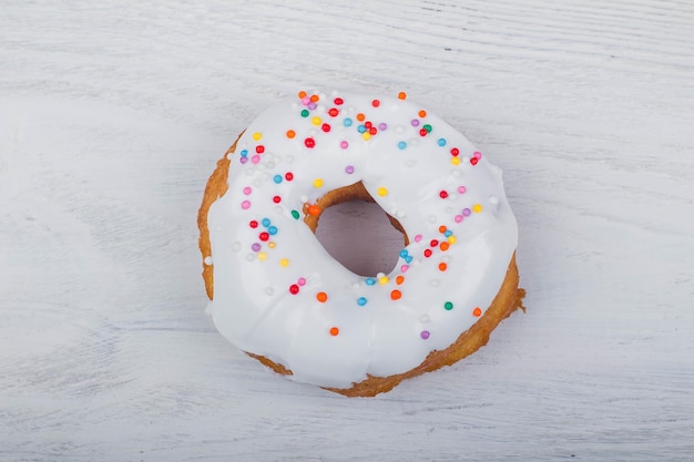 Donut con glaseado blanco sobre fondo blanco de madera