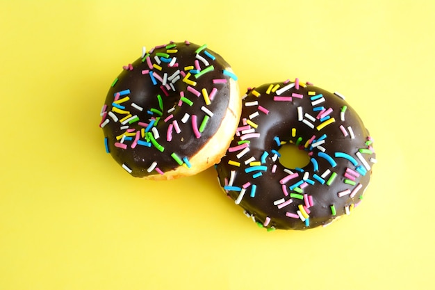 donut con glaseado de chocolate y rociado azul, amarillo, rosa y verde aislado