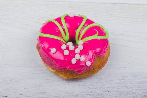 Donut con glaseado rojo sobre fondo blanco de madera