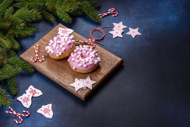 Donut glaseado rosa y malvavisco con adornos navideños en una tabla de cortar de madera