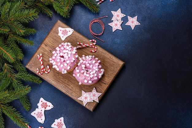 Donut glaseado rosa y malvavisco con adornos navideños en una tabla de cortar de madera