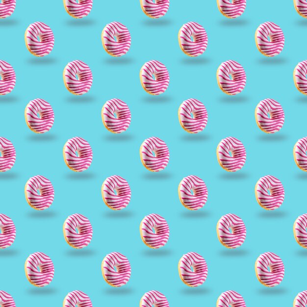 Donut glaseado rosa de patrones sin fisuras sobre fondo azul.