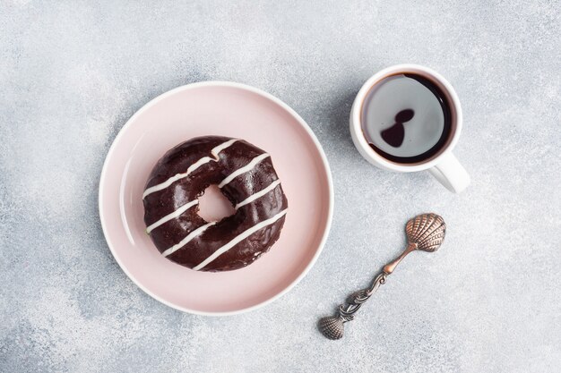 Foto donut en el glaseado y una taza de café en la mesa.