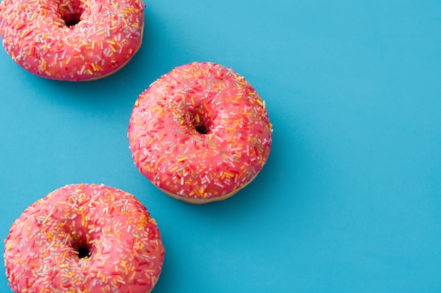 Donut helado rosa con chispitas de colores sobre azul