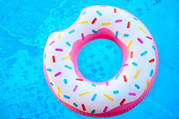 Donut inflable colorido en piscina azul