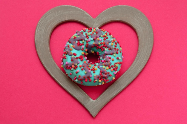 Donut en un marco en forma de corazón sobre un fondo magenta