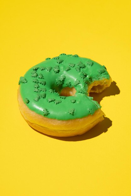 Donut mordido en verde sobre un fondo amarillo foto de estudio vertical