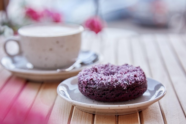 Donut natural sin azúcar y capuchino en mesa de madera Tiempo de café estético al aire libre