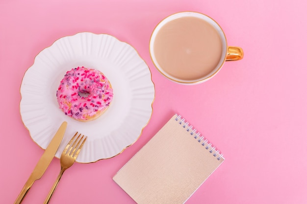 Donut no prato, faca e garfo, xícara de café