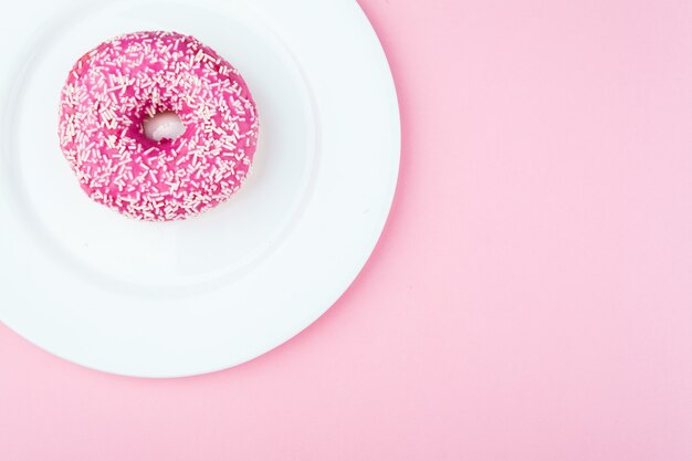 Donut rosa con chispitas en la placa blanca.