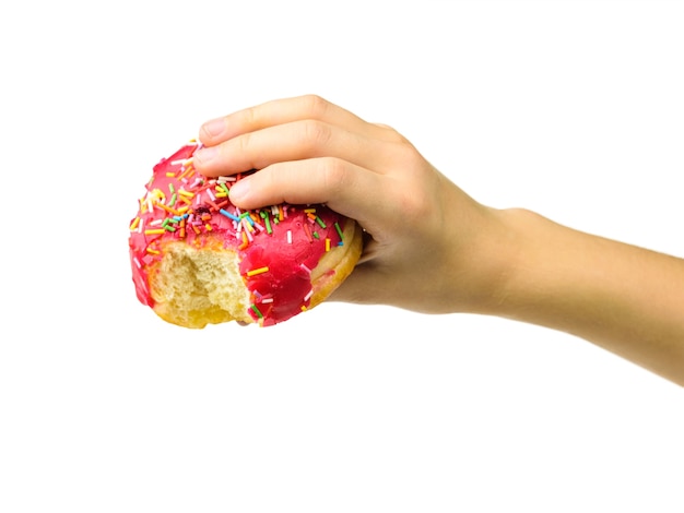 Un donut rosa en la mano de un niño con un borde mordido aislado. Repostería dulce de panadería.