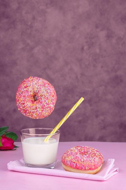 Donut rosa volador con un vaso de leche