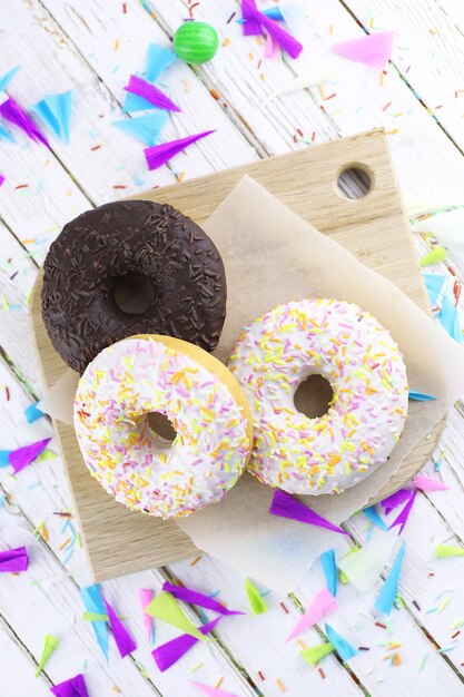 Donut sobre un fondo blanco de madera y una dispersión de adornos dulces