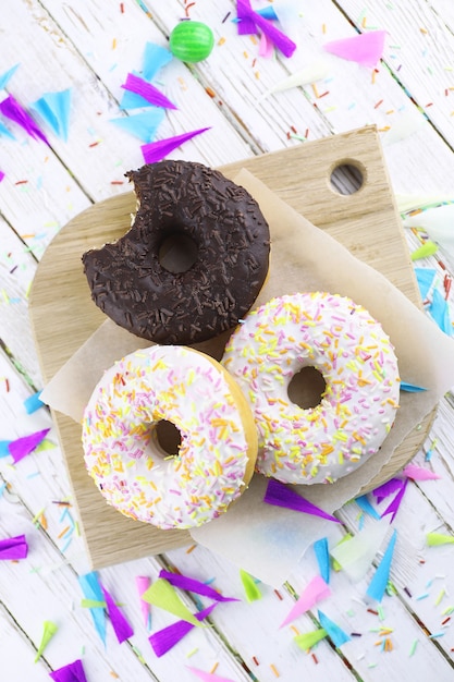 Donut sobre un fondo blanco de madera y una dispersión de adornos dulces