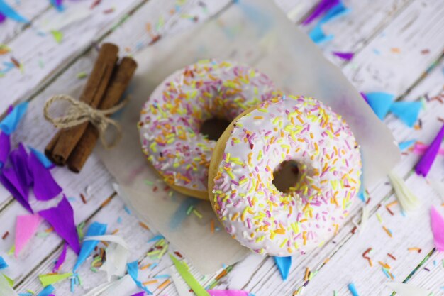 Donut sobre un fondo blanco de madera y una dispersión de adornos dulces