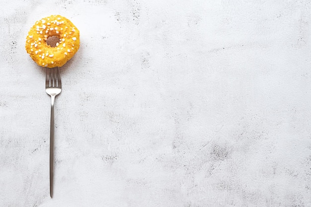 Donut en un tenedor plano yacía sobre fondo gris