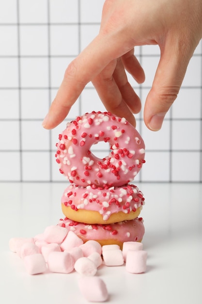 Donut und Marshmallow auf einem hellen Hintergrund mit einer Hand