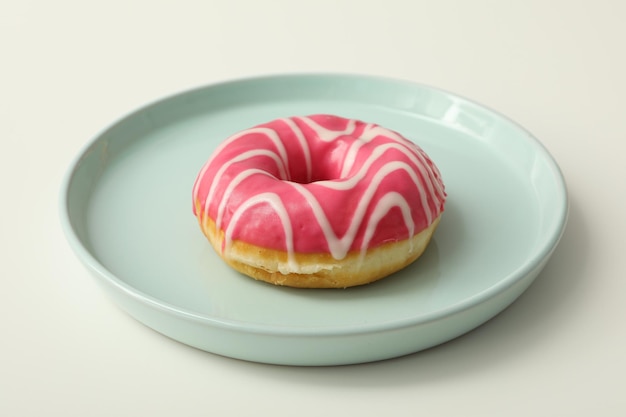 Donut de vidrio rosado en un plato sobre un fondo blanco