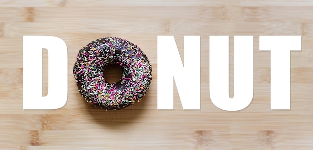 Donut-Wort mit schokoladenglasiertem Donut anstelle von 'O'-Buchstabe, auf Holztisch.