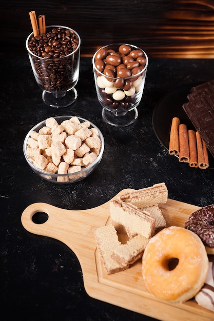 Donuts, amendoim em chocolate e grãos de café em fundo de madeira