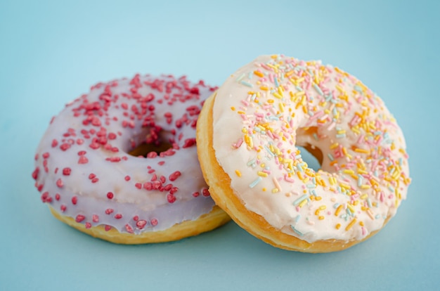 Donuts americanos vitrificados tradicionais no fundo azul pastel. Fechar-se.