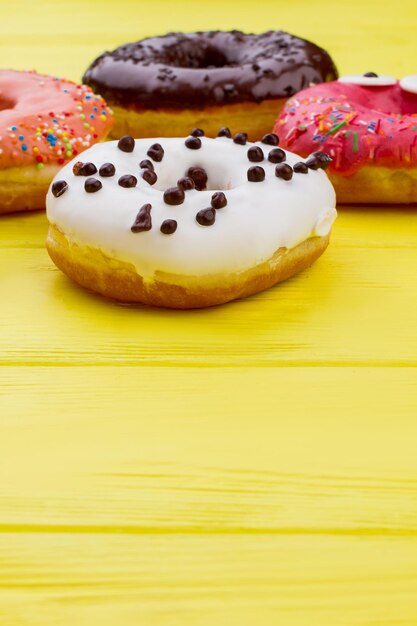 Foto donuts auf farbigem holzhintergrund mit kopierraum. glasierte runde kuchen. köstliche süßigkeiten mit zuckerguss.