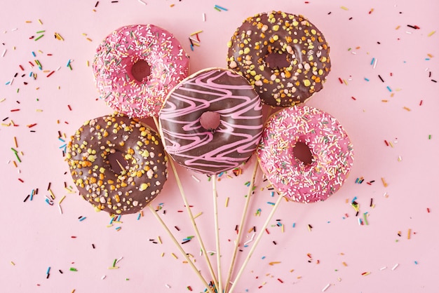 Donuts auf rosa Hintergrund mit Konfetti. Kreativer Food-Minimalismus-Stil