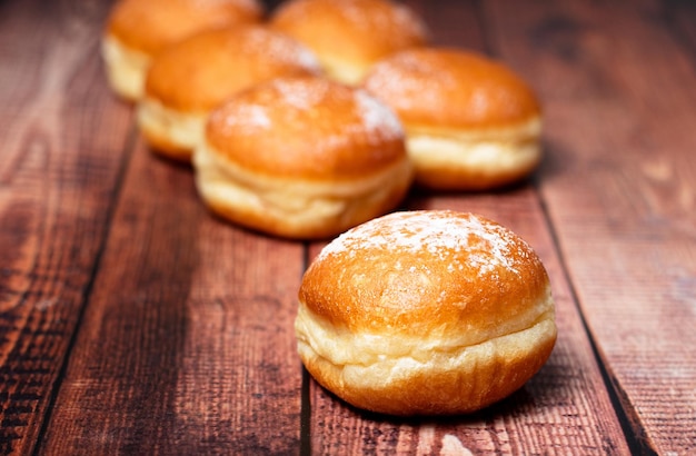 Donuts austríacos e alemães ou krapfen Faschingskrapfen berliner com creme em fundo de madeira