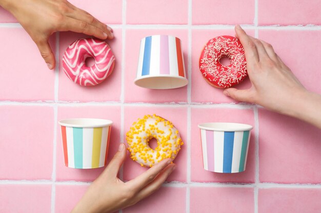 Donuts en una baldosa rosa con tazas de papel