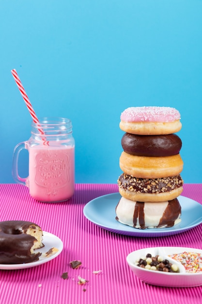 Donuts y batido de fresa sobre fondo rosa y azul.