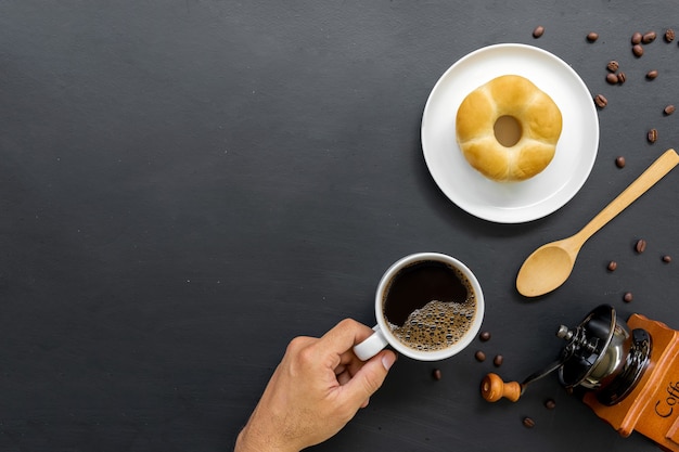 Donuts de café caliente frijol y molinillo de mano sobre fondo de mesa negro