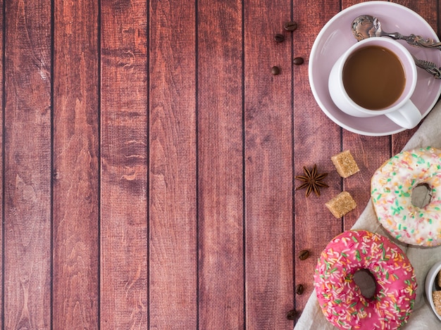 Donuts y café en la mesa de madera. Vista superior con espacio de copia.