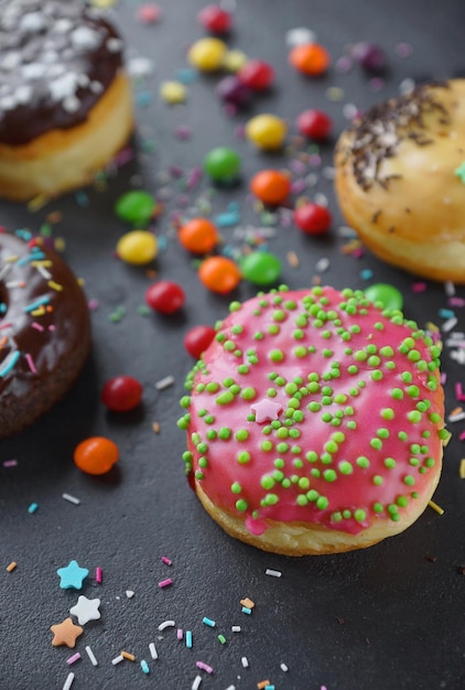 Donuts y chispitas de colores sobre fondo de piedra oscura, fiesta, primer plano, enfoque selectivo