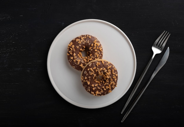 Donuts de chocolate glaseados en un plato sobre la mesa de madera