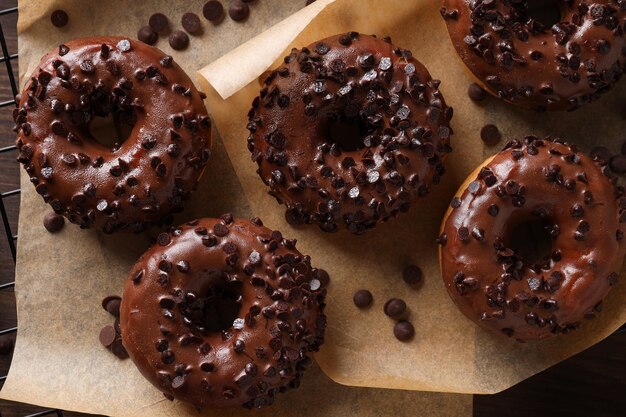 Donuts de chocolate sobre papel sobre fondo de madera vista superior