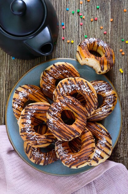 Donuts clásicos caseros con copos de chocolate y coco sobre un fondo de madera. Vista superior. endecha plana