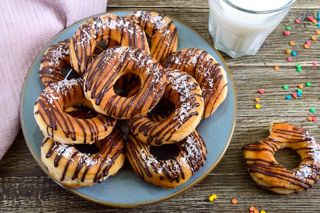 Donuts clásicos caseros con copos de chocolate y coco sobre un fondo de madera.