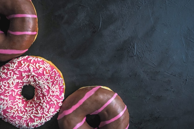 Donuts de colores sobre la mesa de piedra negra. Vista superior