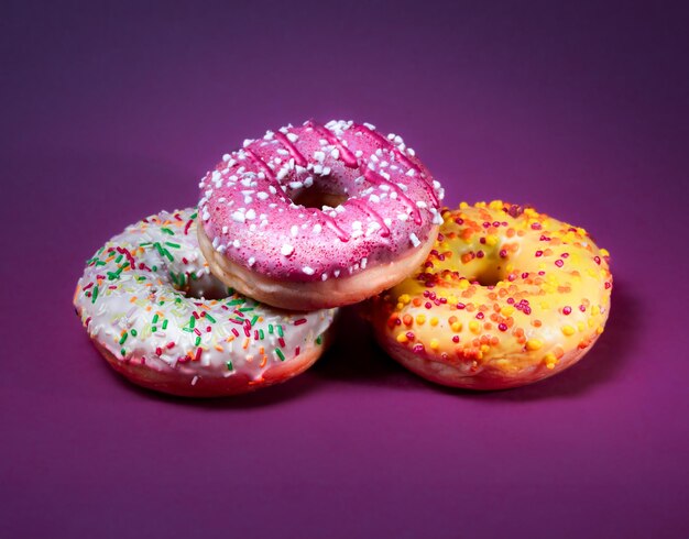 Foto donuts coloridos con glaseado y salpicaduras de fondo pastel vacío