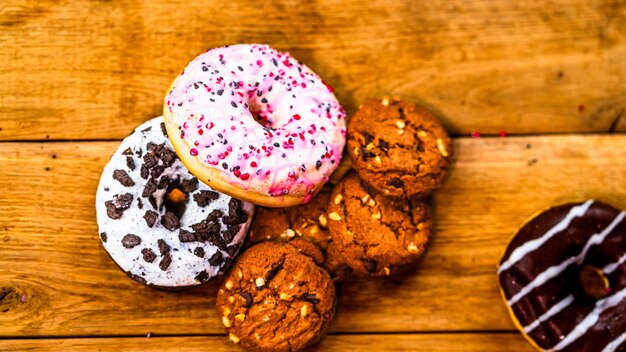 Donuts coloridos sobre mesa de madera Dulce glaseado de azúcar con chispas glaseadas donut con glaseado de chocolate Vista superior con espacio para copiar