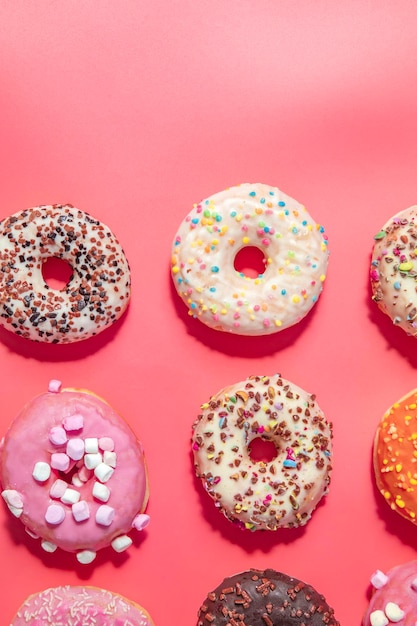 Donuts com glacê em fundo rosa pastel rosquinhas doces vista superior sortidas com vários gl de chocolate