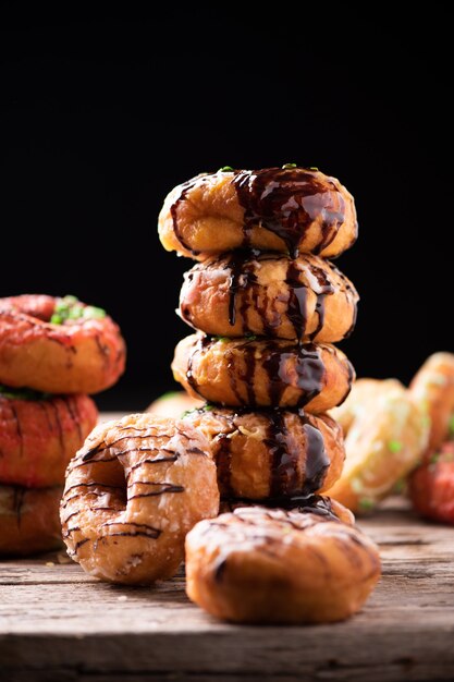 Donuts cubiertos con salsa de chocolate sobre un plato de madera